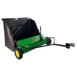 De veegmachine achter een tractor op het gazon